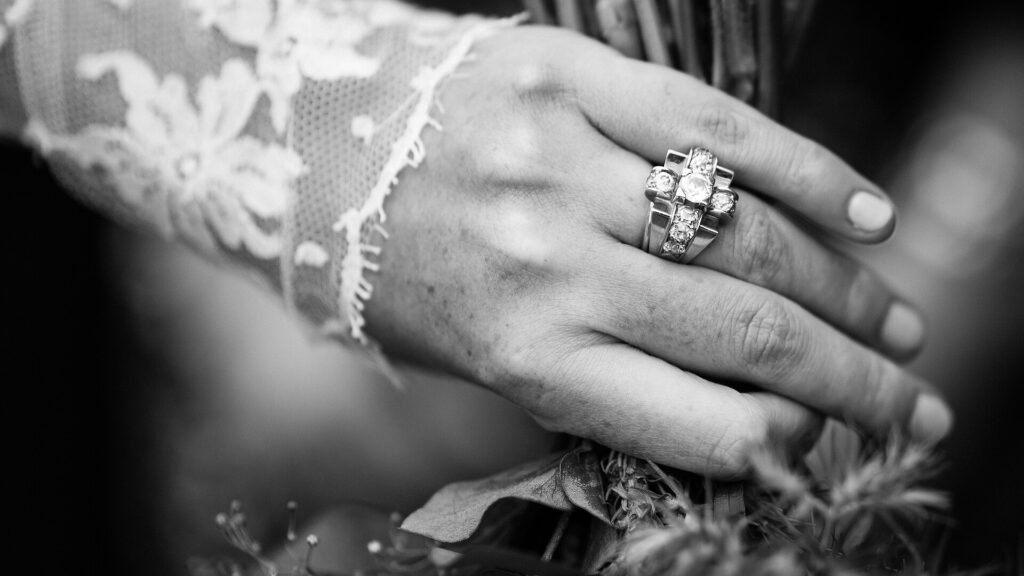 Close-up of a hand wearing fine jewellery against a lace sleeve