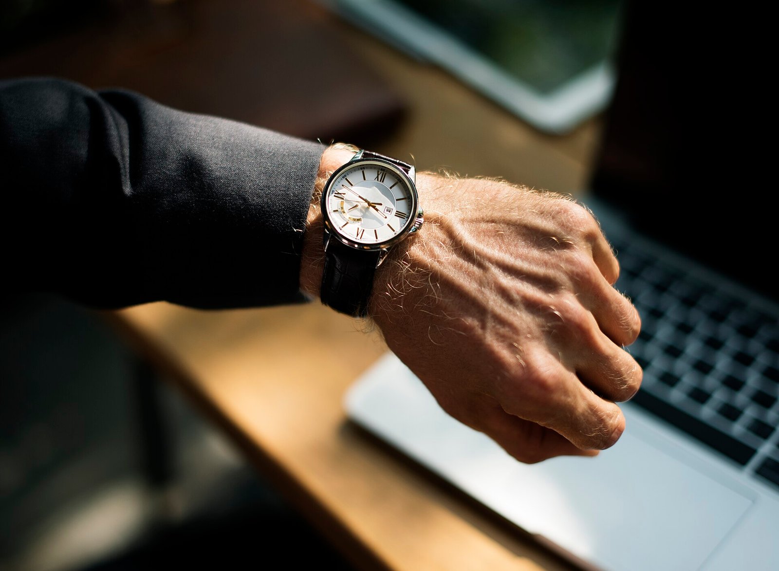 Elegant luxury wristwatch on a man in a dark suit at his desk