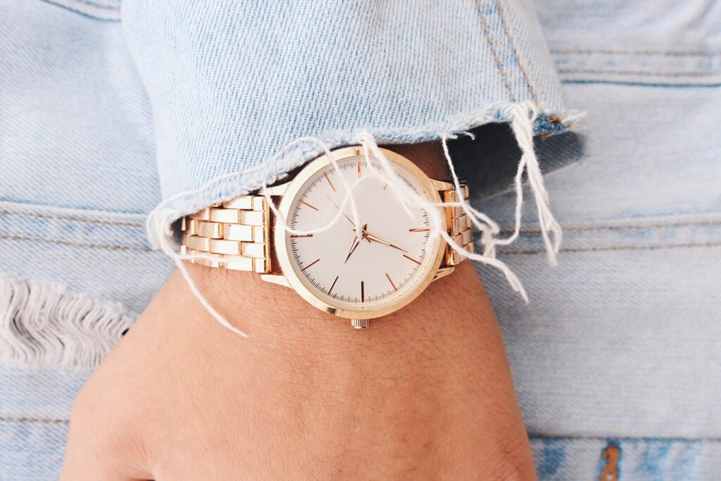 Gold wristwatch worn with a relaxed denim cuff