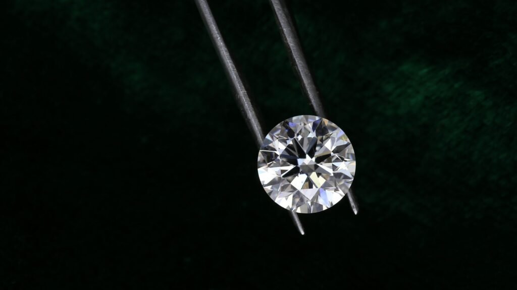 Round brilliant diamond held in tweezers for inspection