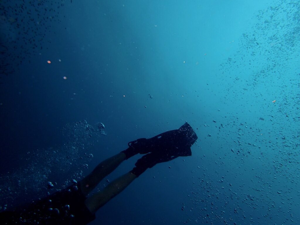 Scuba diver swimming in deep blue water over a shipwreck