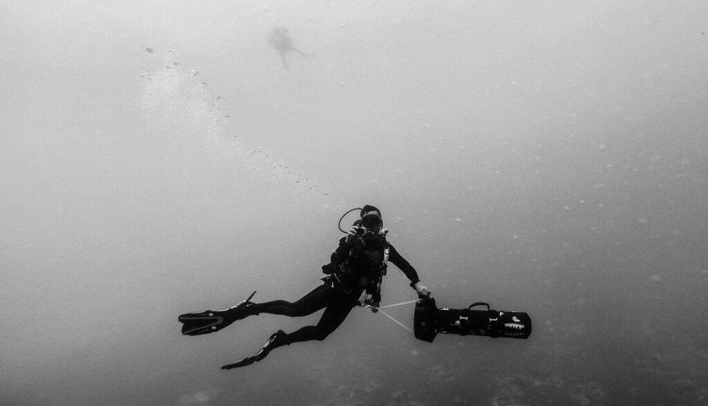 Silhouette of a diver descending through misty underwater light