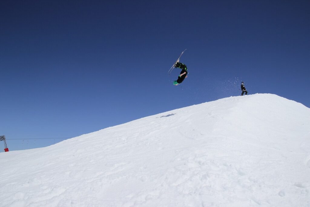 Skier jumping against a deep blue sky above a snowy slope