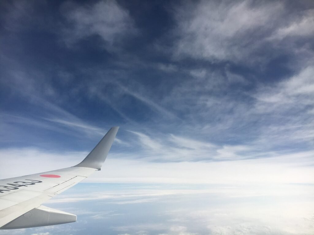 View from an aircraft window above scattered clouds and blue sky