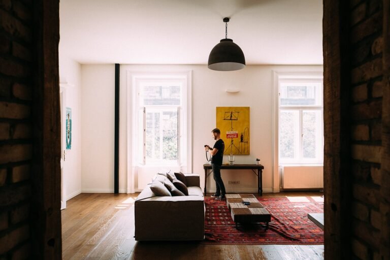Warm open apartment interior seen through a doorway, with a pendant light and timber floor