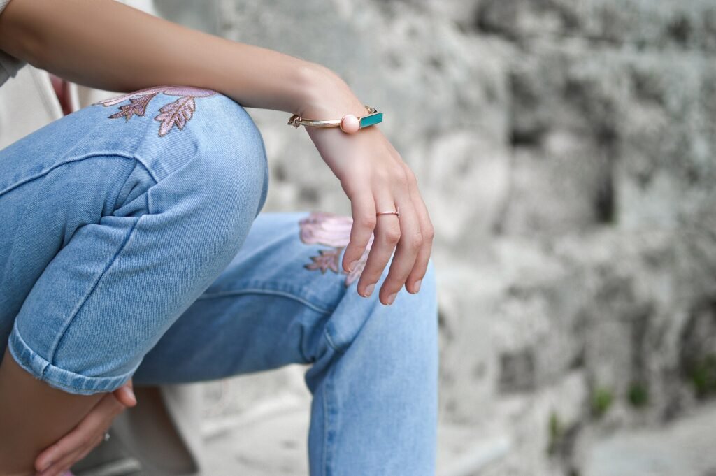 Woman in relaxed denim wearing a gold bracelet on her wrist